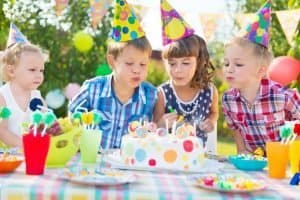 Kids Blowing Candles On Cake At  Birthday Party