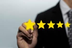 businessman touching one of 5 gold stars representing customer experience management