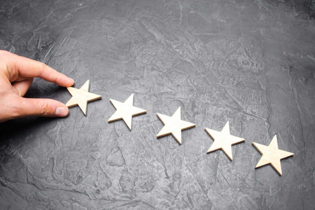 Hand placing a fifth star on a surface, representing ESM compliance and security.