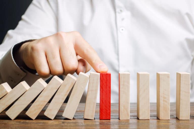 Stopping domino effect with red block for business continuity and risk management.