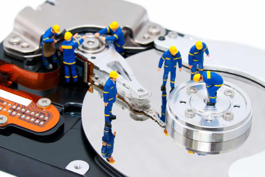 Miniature workers performing data recovery on a hard drive.