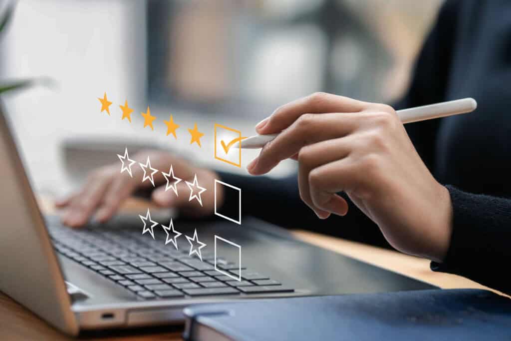 Hand of a woman in front of a laptop, rating stars illustrating how to choose the right AI automation agency.