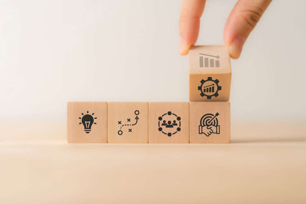 Stacked wooden blocks with business icons representing business continuity and resilience strategies.