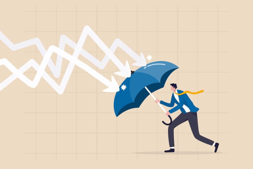 A man with an umbrella shields against downward arrows, symbolizing financial resilience during economic downturns.