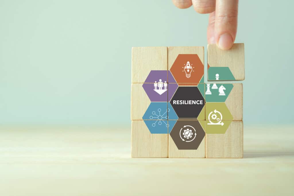 Wooden blocks with various icons forming the word "resilience," illustrating elements of business resilience.