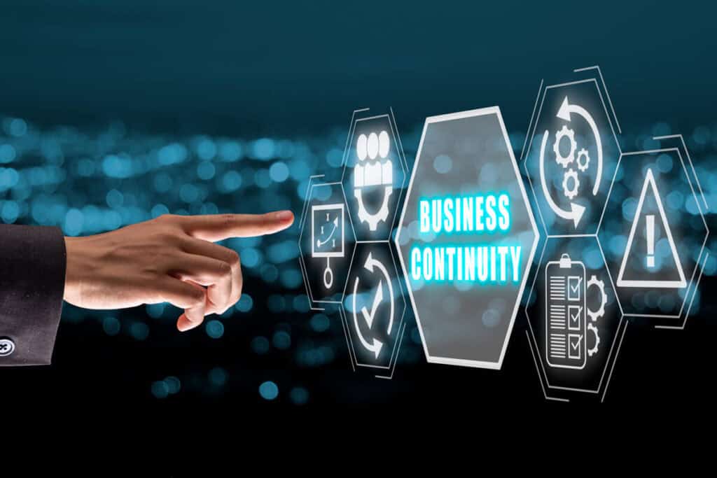 Hand of a man toching a digital screen with an hexagon at the center and the words "Business continuity" within as an example of what is a business continuity management system